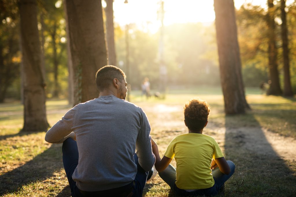 Padre e hija sentados en la hierba en el parque