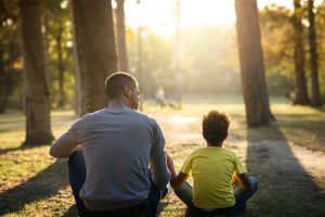 Padre e hija sentados en la hierba en el parque